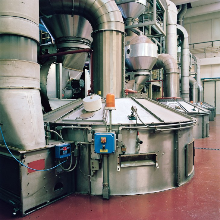 Industrial coffee roasting machines with large metal tanks and pipes at the Illy factory.