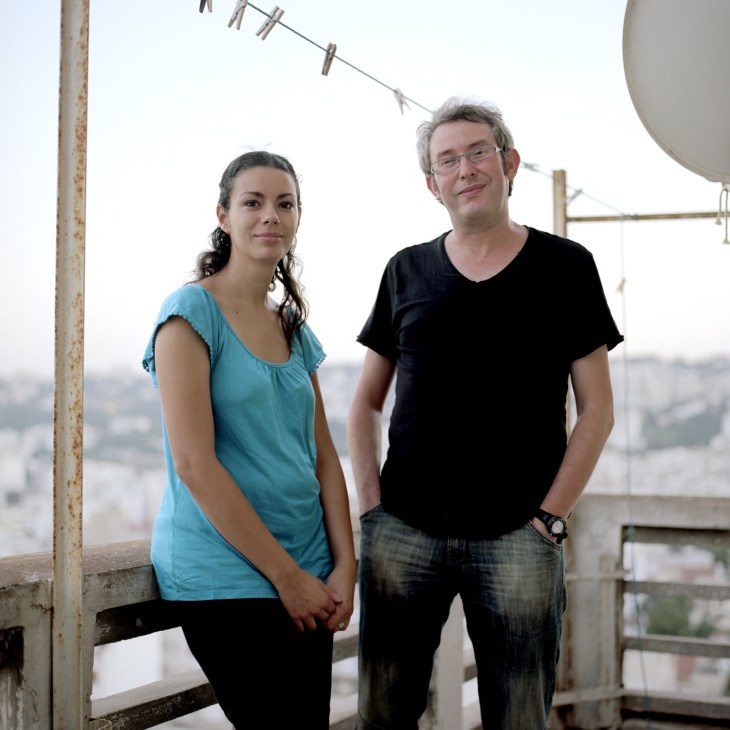 Artist Amina Menia and playwright Mostafa Benfodil stand on a high rooftop overlooking Algiers.