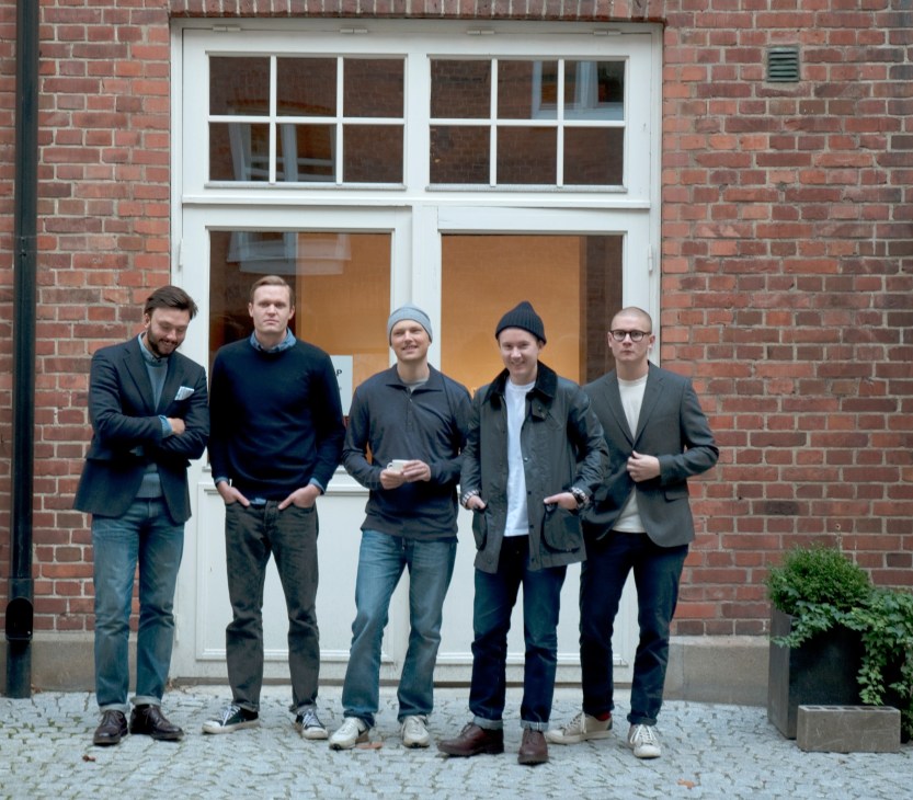 Five men stand outside a brick building storefront at Très Bien in Stockholm.