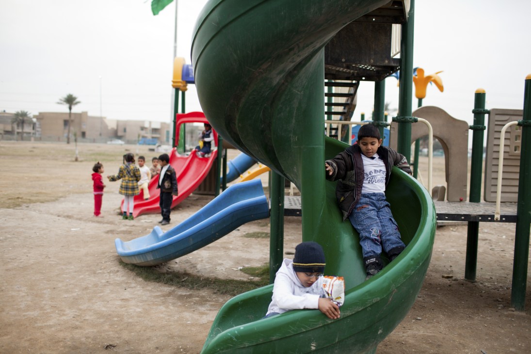 Children playing on a new playground with colorful slides and equipment in Baghdad.