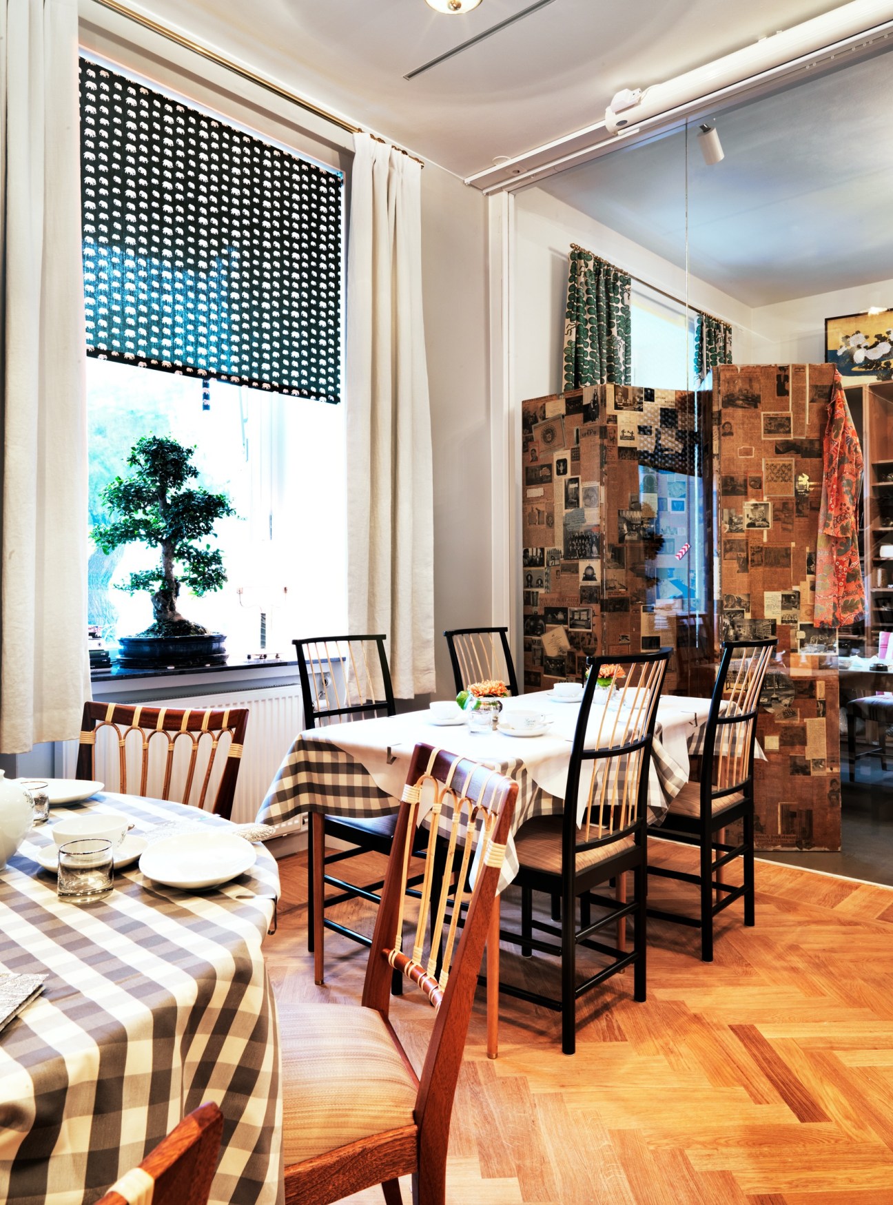 Tea rooms at Svenskt Tenn with dining tables, patterned textiles, wooden chairs, and display wall.