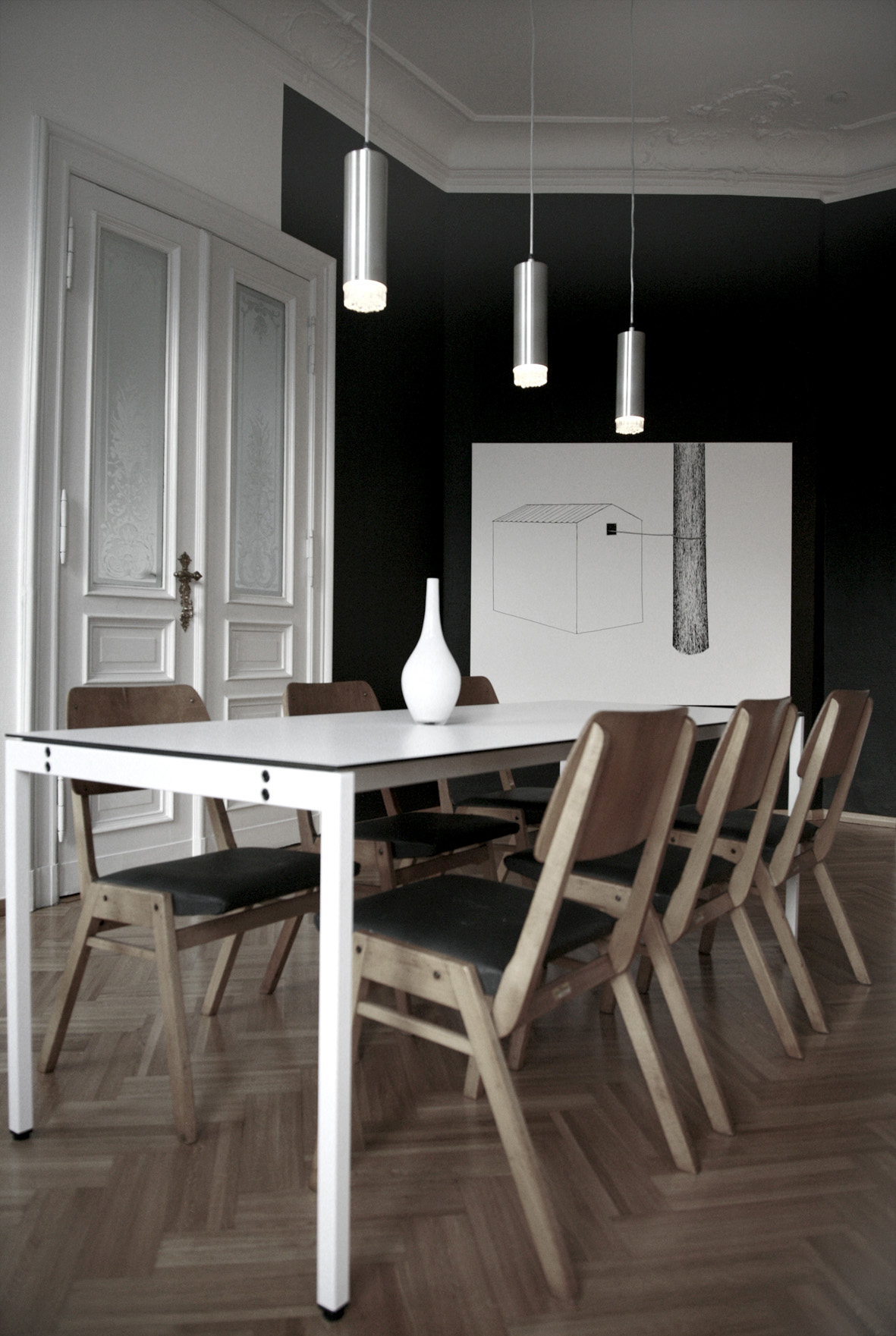 Modern dining room with white table, wooden chairs, pendant lights, and black accent wall at Sankt Oberholz in Berlin.