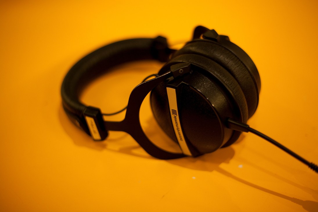 Black over-ear headphones with coiled cable on yellow background