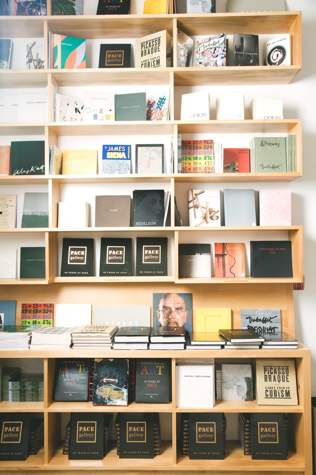 Wooden shelving unit displaying art books, exhibition catalogs, and Pace Gallery publications.