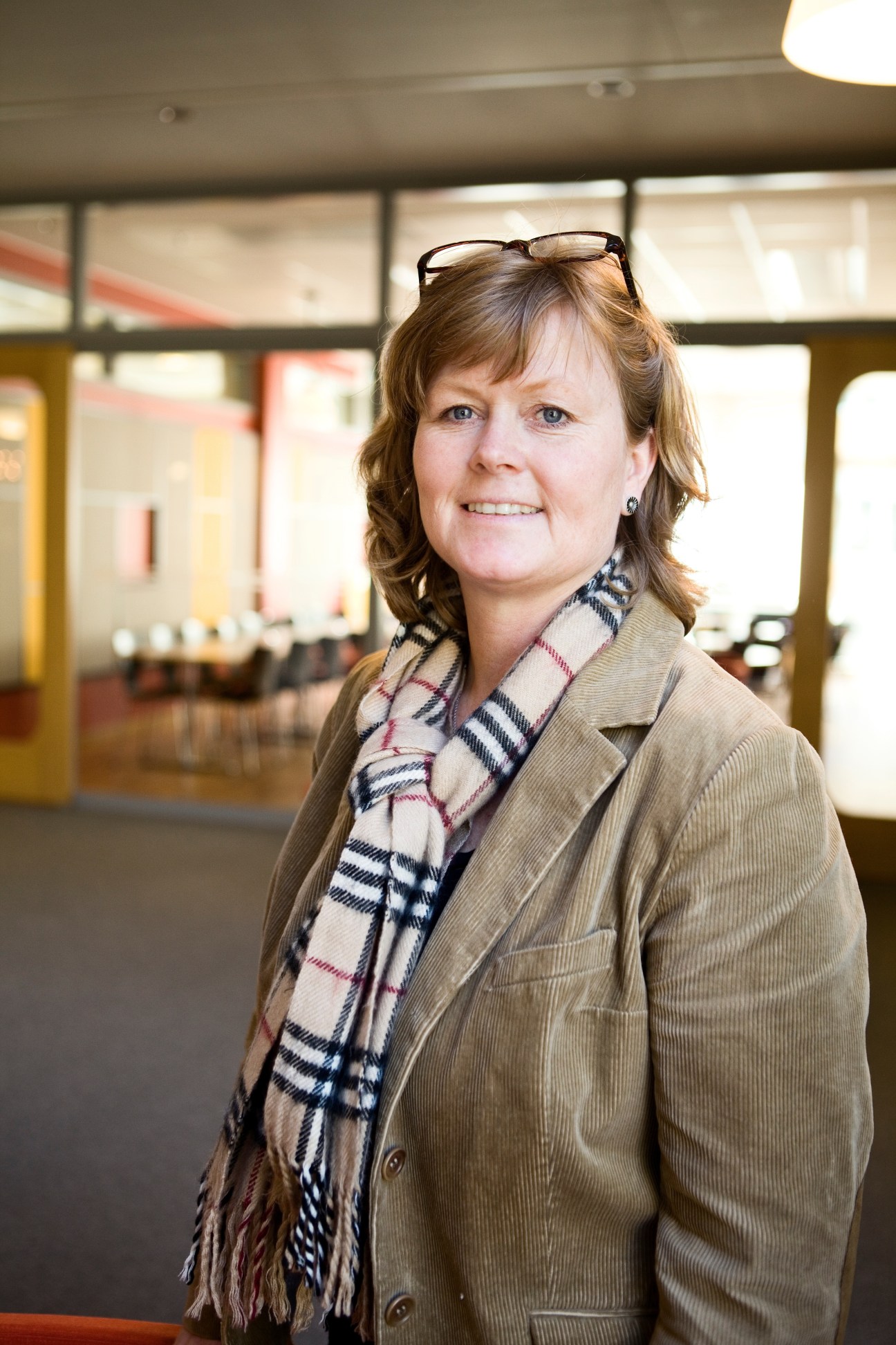 Charlotte Brogren, general director of Vinnova, poses in a modern office with large windows behind her.