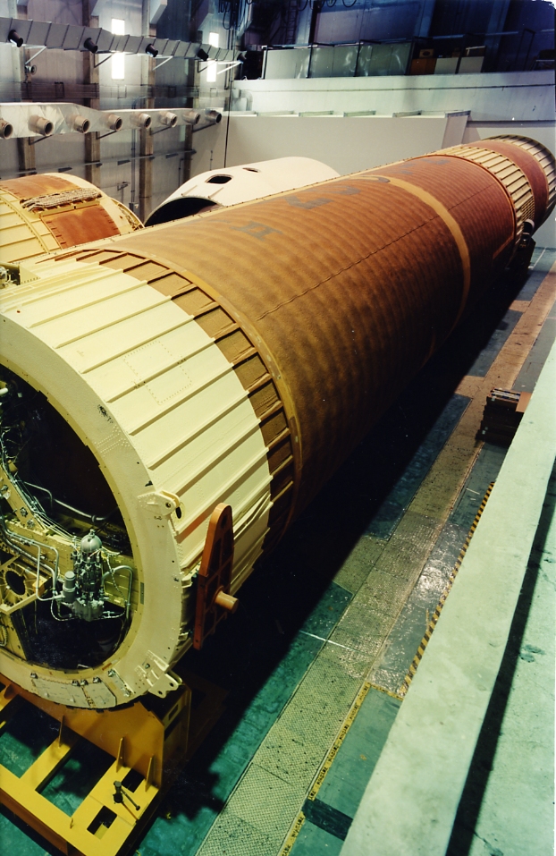 H-II launch vehicle with gold-coloured fuel tank and white payload section in an assembly building.