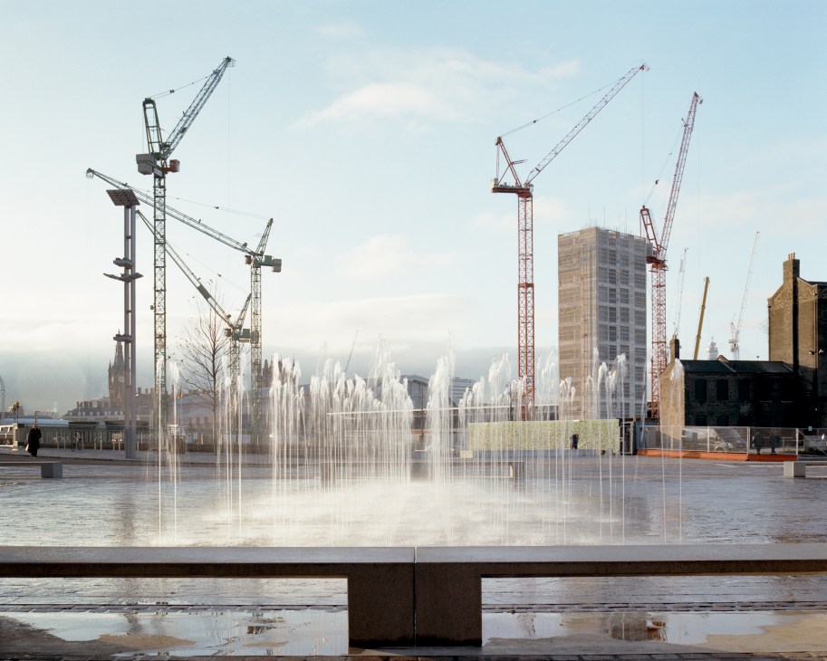 Granary Square with fountains, construction cranes, and King's Cross Station in the background.