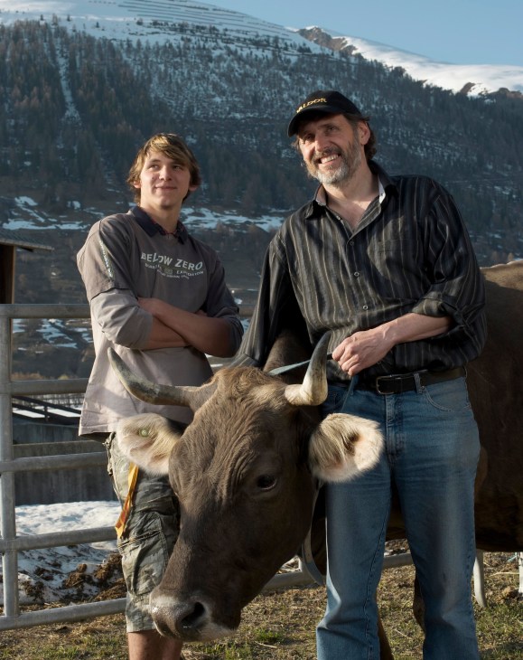 Farmer Andy Imfield and his son Samuel pose with a pregnant dairy cow in the Swiss mountains.
