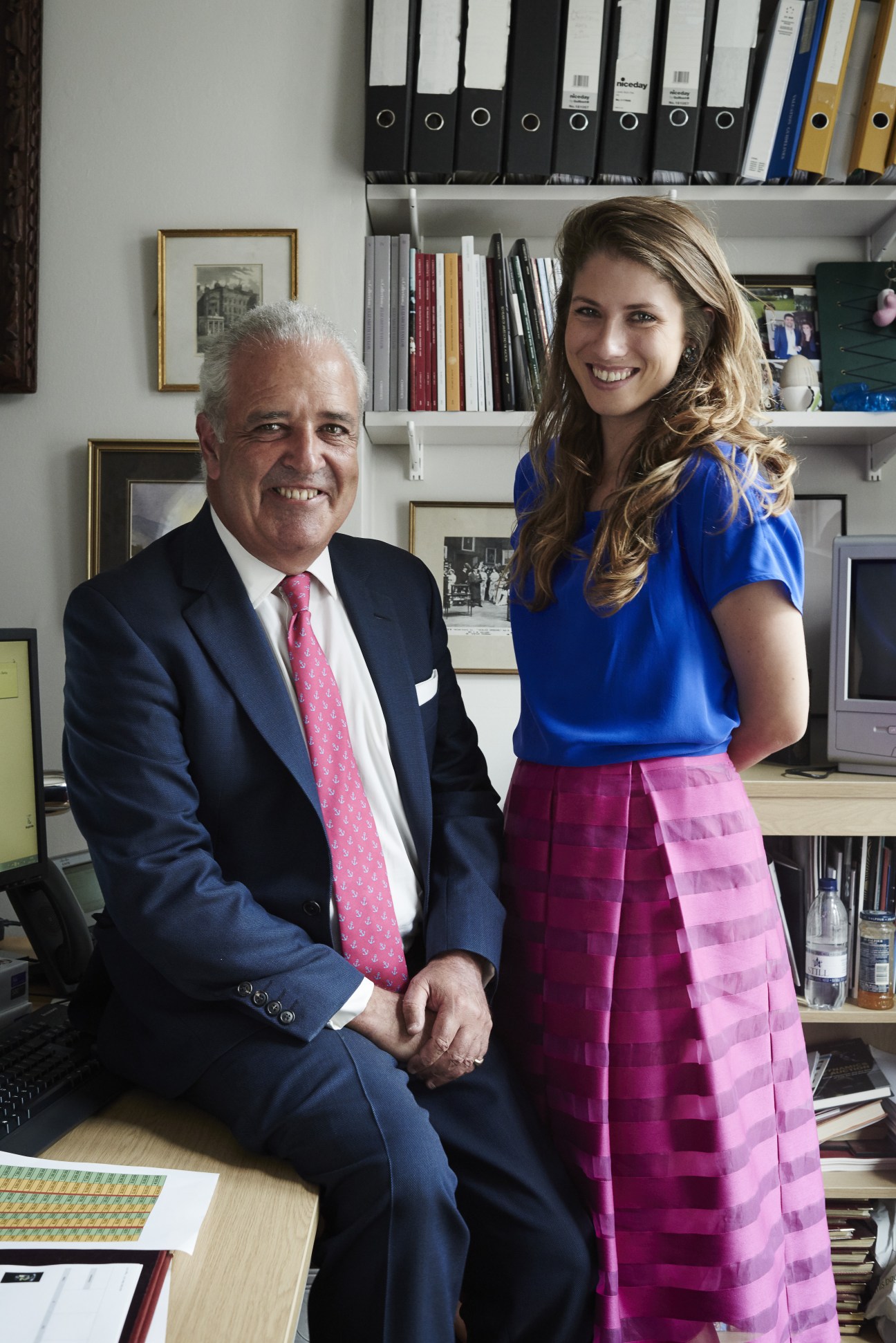 Hugh Edmeades and Marlous Jens shake hands in Christie's office with bookshelves behind them.