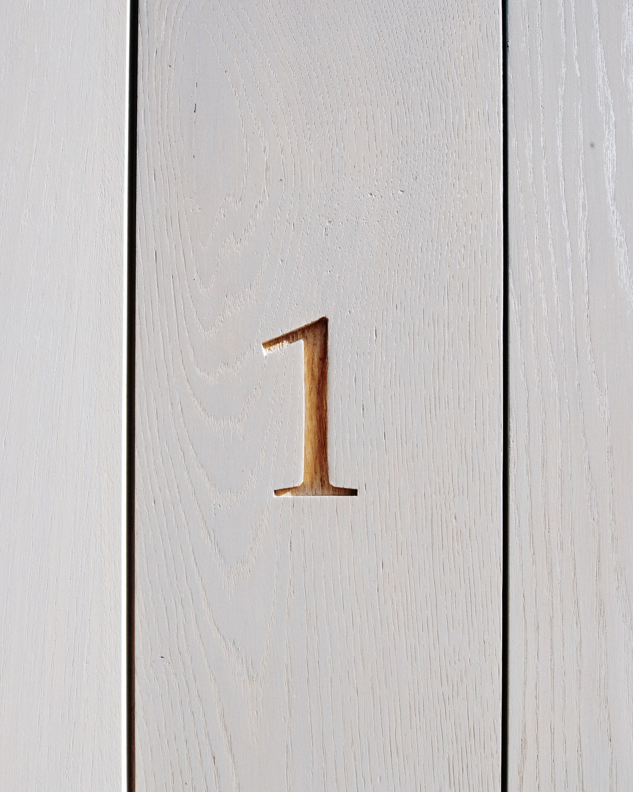 Wooden house number 1 carved into light oak facade