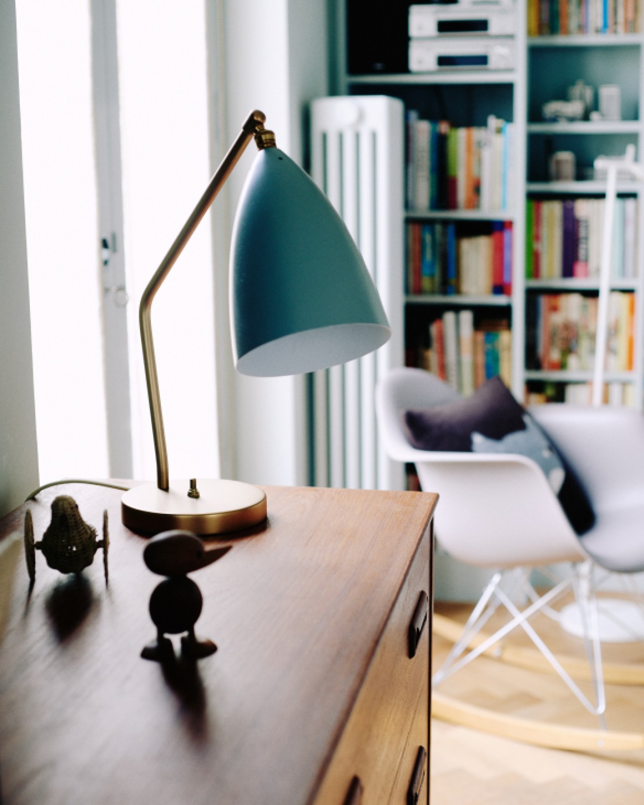 Gubi Grasshopper table lamp with teal shade and brass base on wooden desk