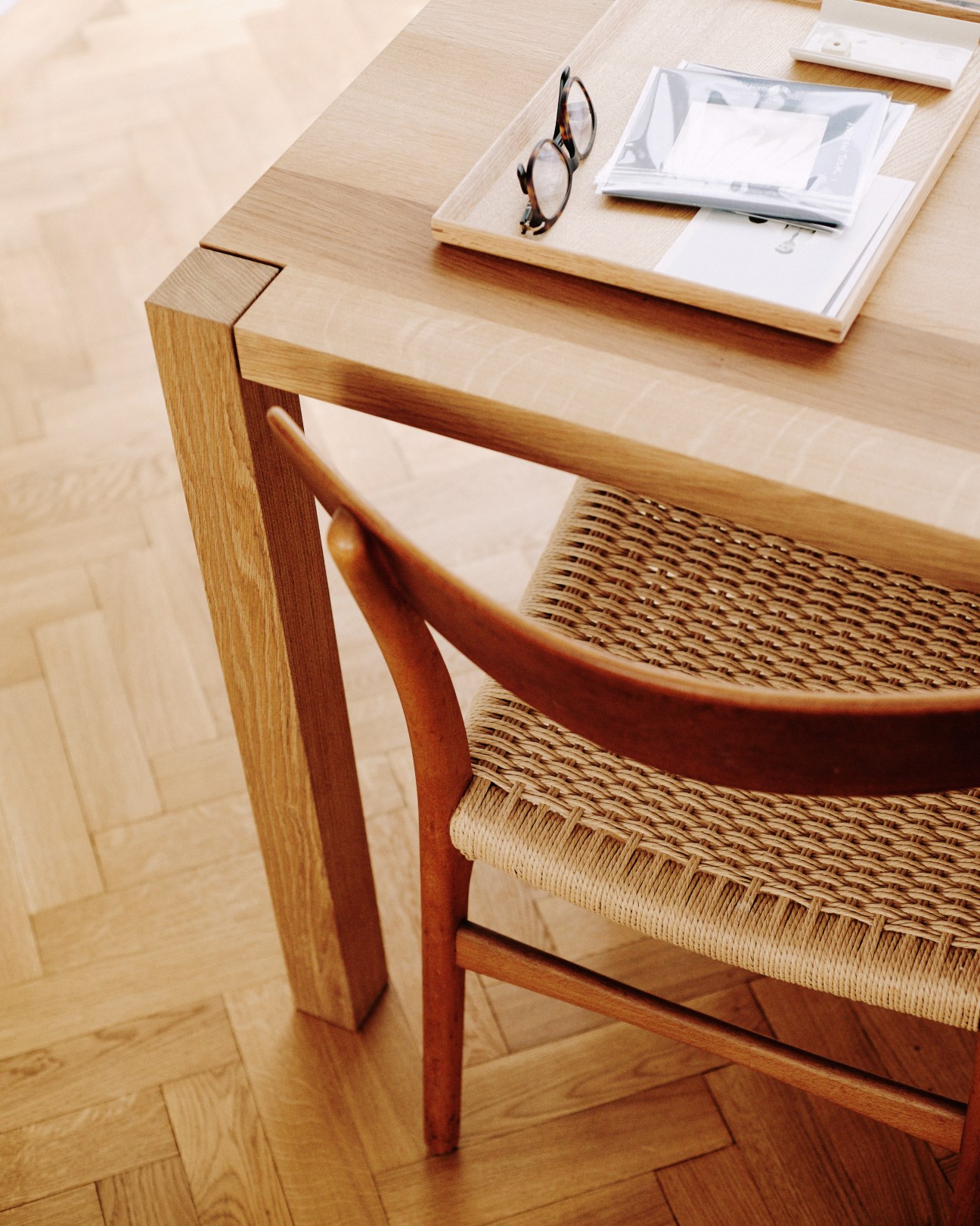 Hans J Wegner wooden chairs with woven rush seats positioned at a light oak desk.