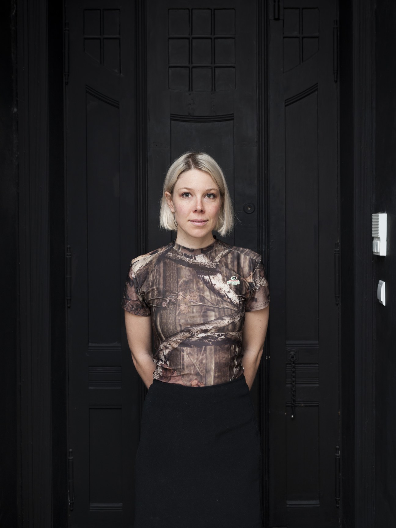 Canadian artist Emmy Skensved poses for a portrait against a black door
