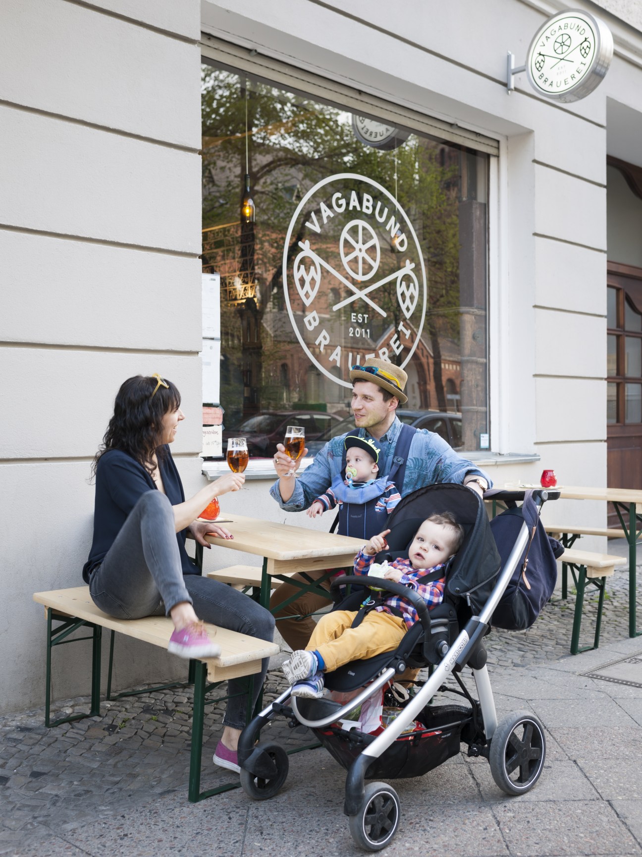Family enjoying drinks outside Vagabund Brauerei brewery in Wedding, Berlin.