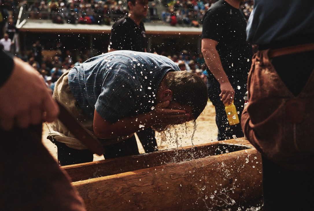 A Swiss wrestler cools off by dunking his head in water during a break between rounds at the Brünig Schwingen wrestling event.