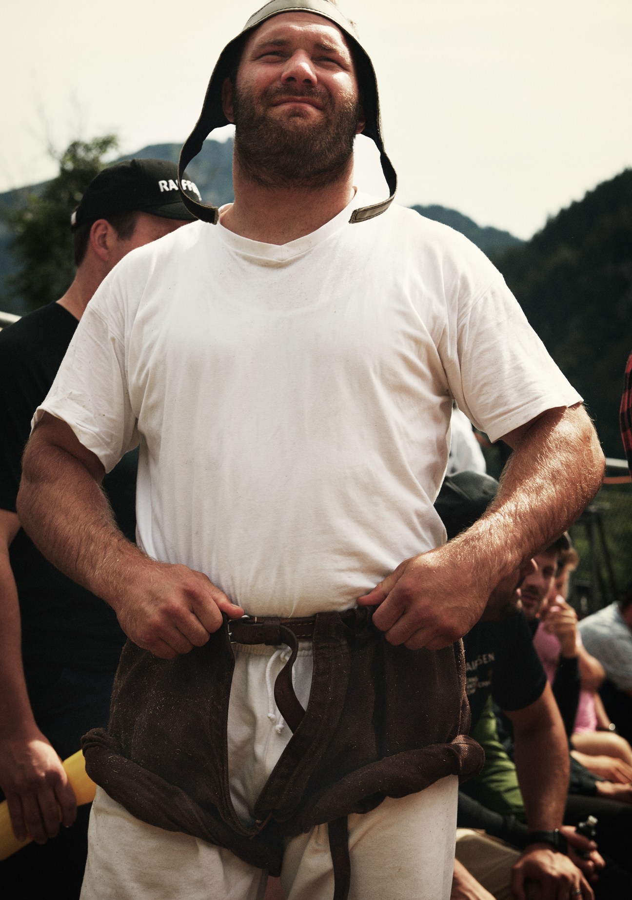 Bearded man in white t-shirt and traditional burlap wrestling shorts at the Brünig Schwingplatz.