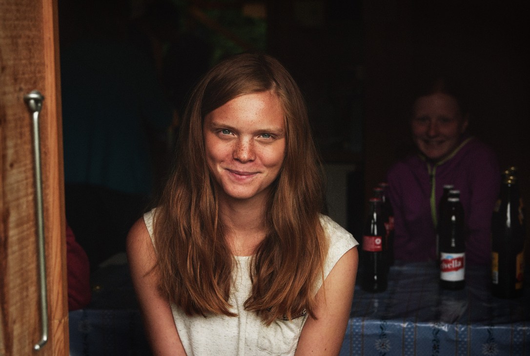 Young woman with long brown hair smiling at a Schwingen wrestling event in Switzerland.