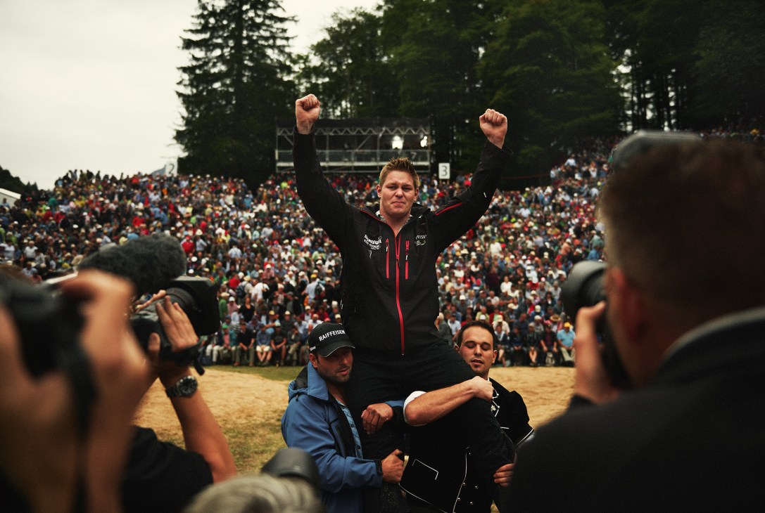 Bernhard Kämpf celebrates victory with raised fists before a large crowd at the Brünig Schwingen wrestling championship.