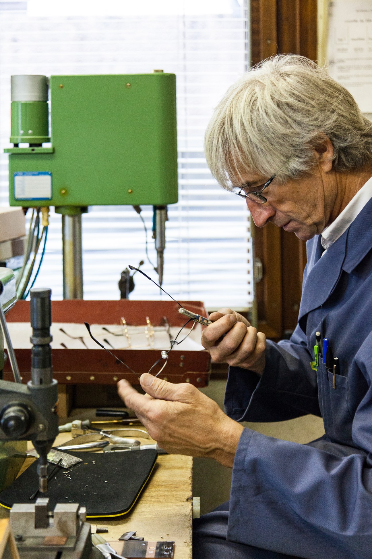 Pierre Hibon working with eyewear components and electronic equipment at the Bourgeat factory.