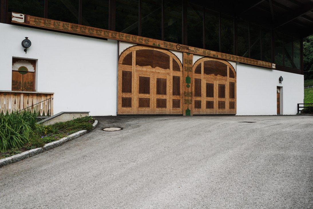 White building with large wooden double garage doors and arched windows in Alpine architectural style.