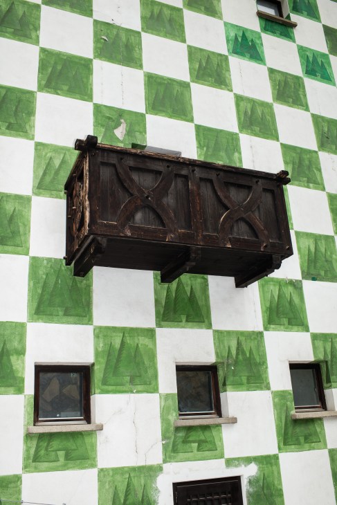 Dark wooden carved bracket on green and white checkered building facade at Forst brewery.