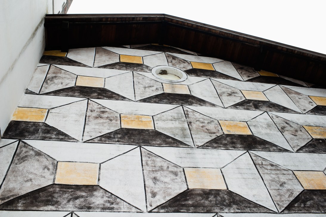 Geometric patterned trompe l'oeil ceiling with diamond shapes in white, black and gold tones.