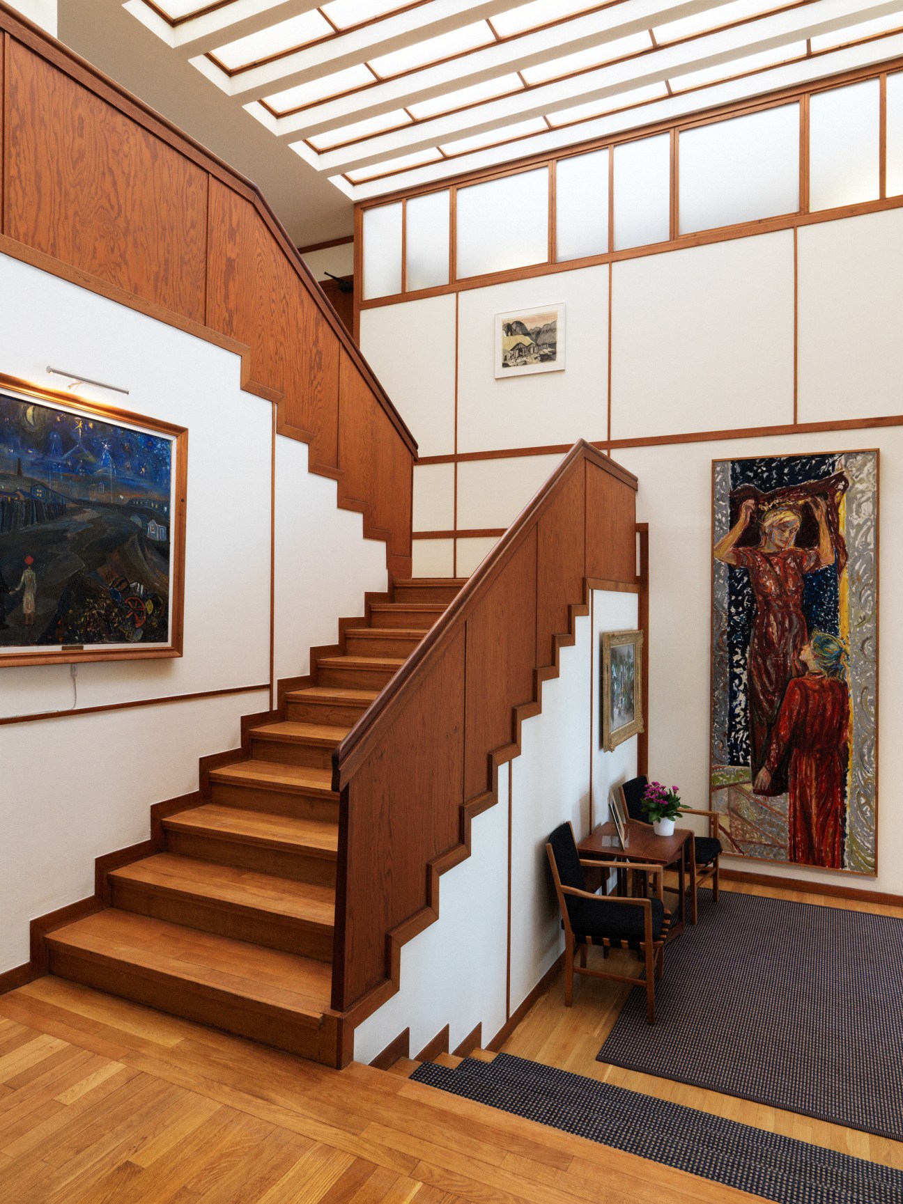 Mid-century wooden staircase with brass railings leading to upper floor in Norwegian embassy.