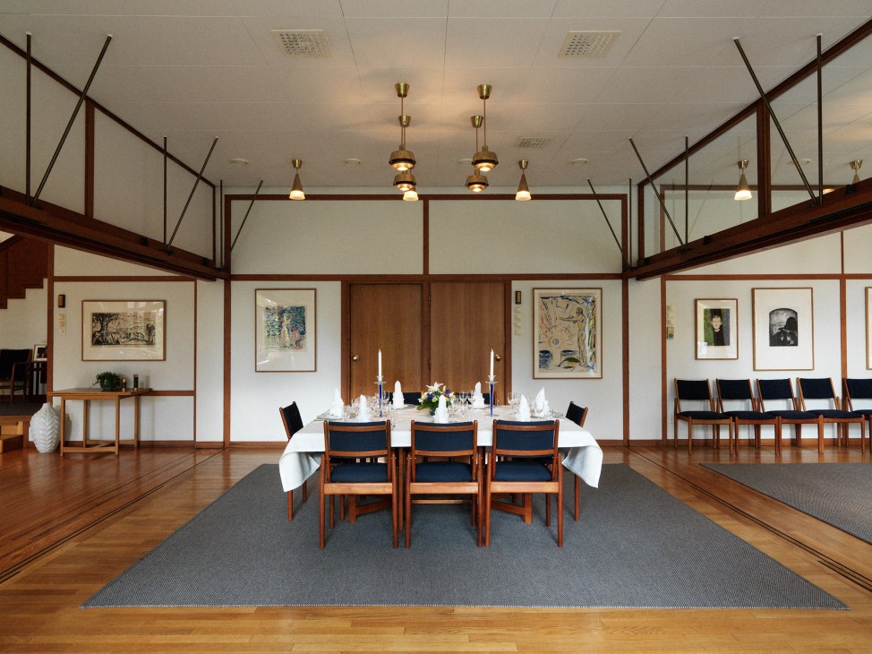 Minimalist dining room with sliding door system, wooden chairs, and artwork on walls.