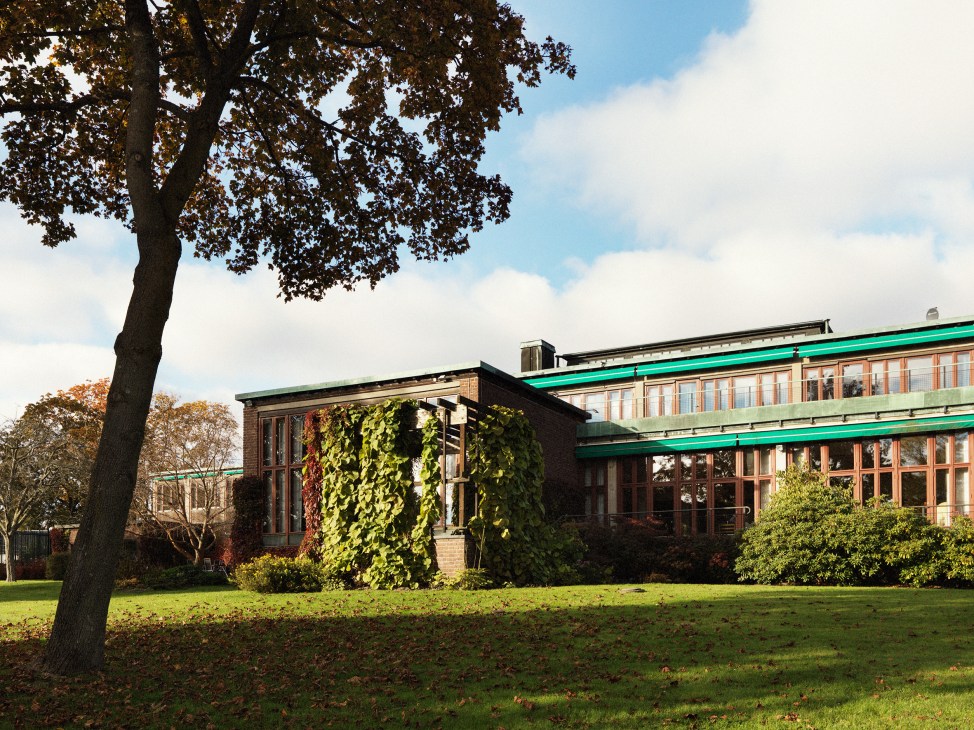 Norwegian embassy in Stockholm designed by Knut Knutsen, a modern brick building with green roof integrated into hillside landscape surrounded by trees.