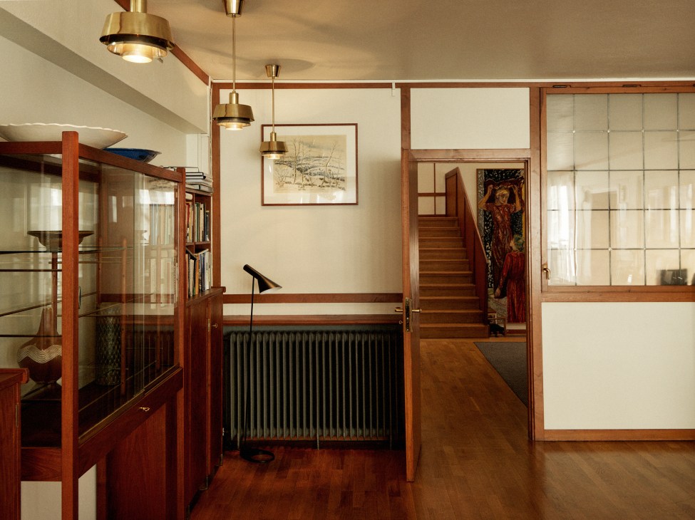 Interior view of the Norwegian embassy drawing room featuring wooden-framed glass cabinets with gridded panels and brass pendant lights.