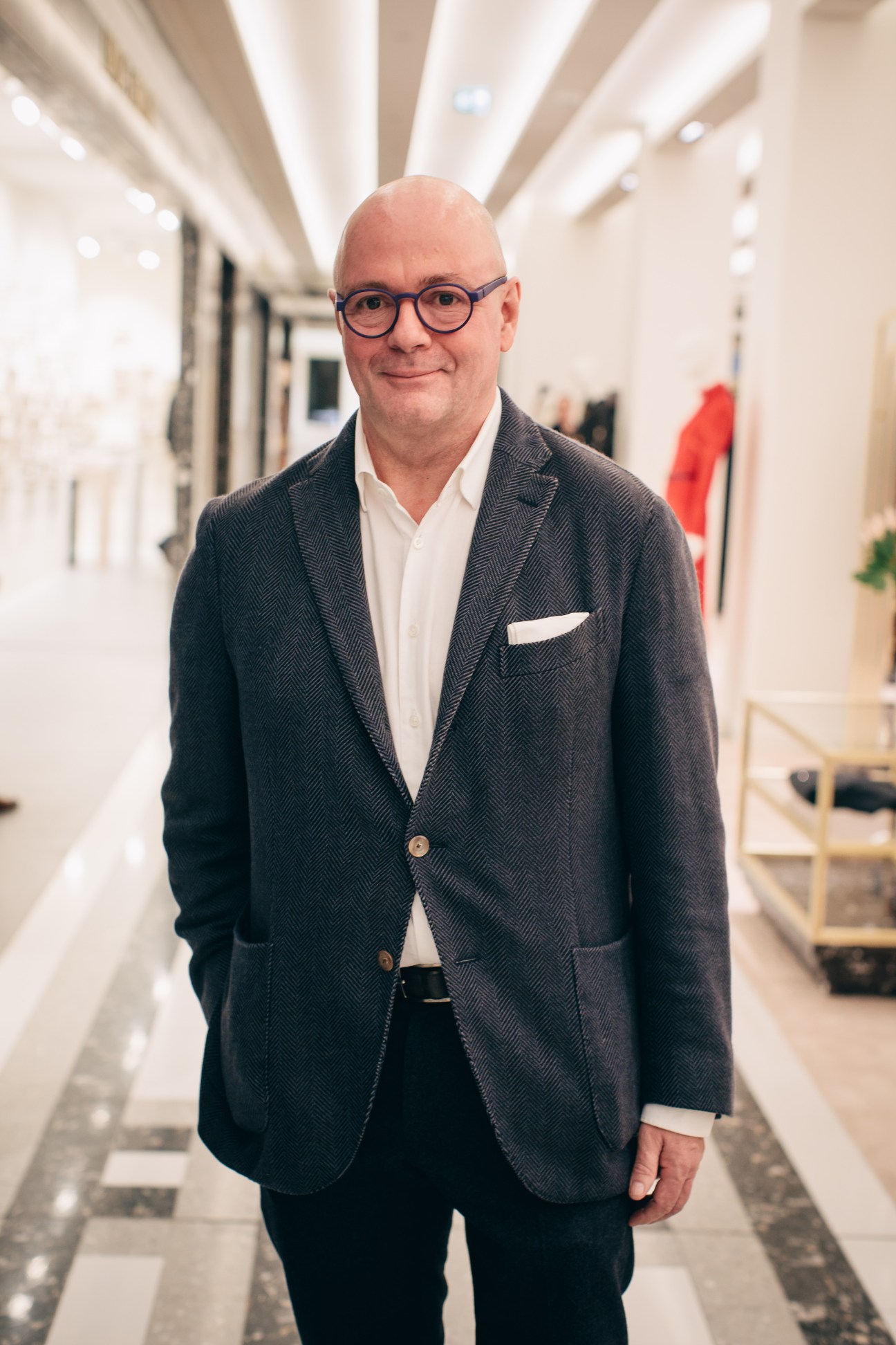 André Maeder, CEO of the Kadewe Group, standing in a modern department store corridor wearing glasses and a dark blazer.