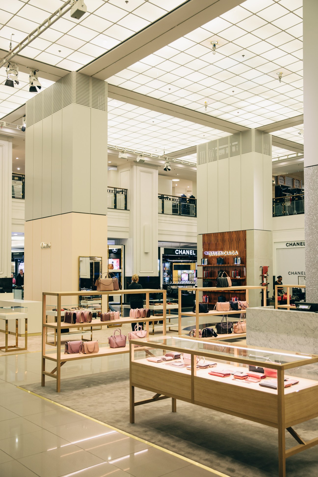 Kadewe's women's fashion department with marble-wrapped displays, golden racks, and luxury brand boutiques including Chanel.