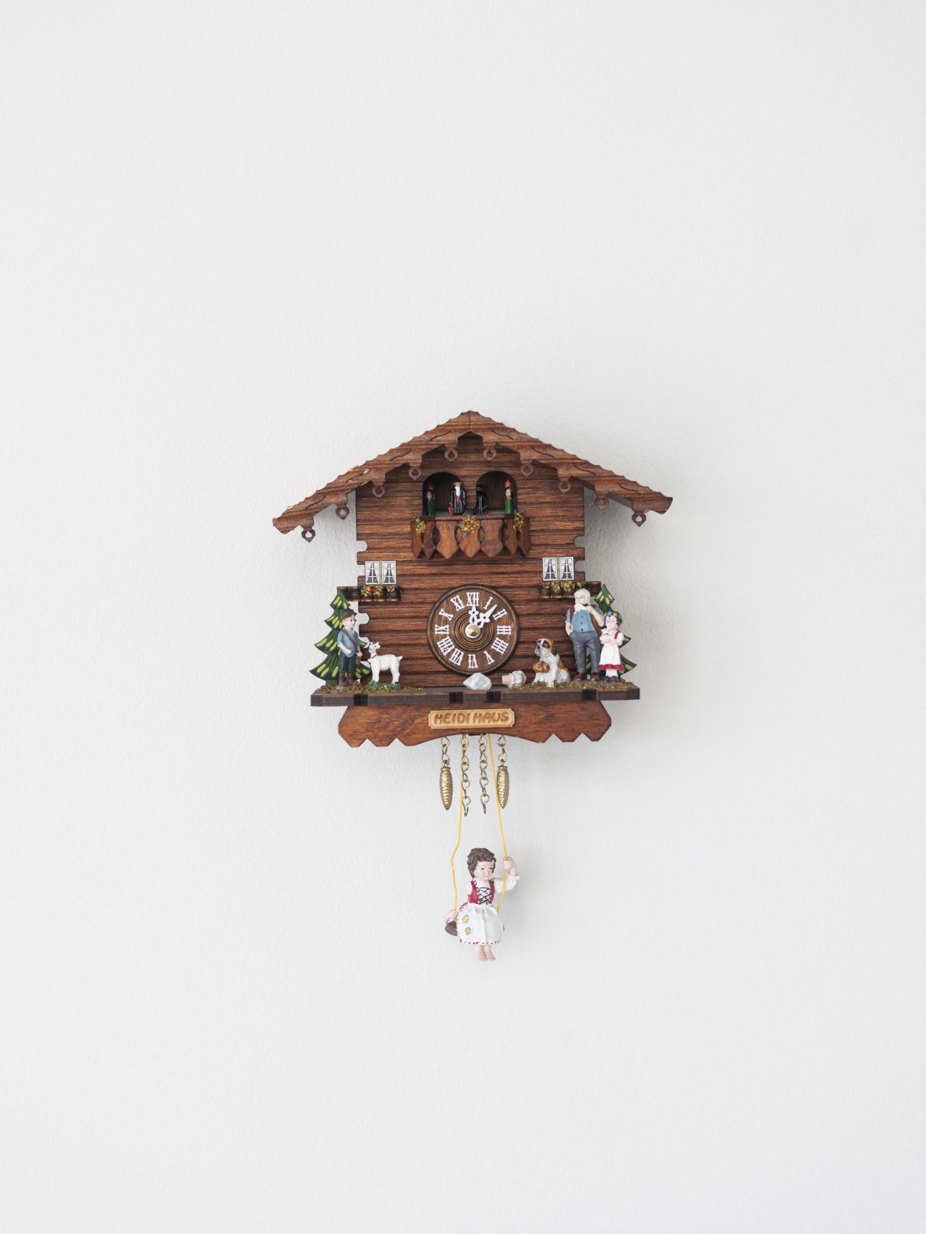 Ornate wooden cuckoo clock with Alpine chalet design, featuring a swinging figure below.