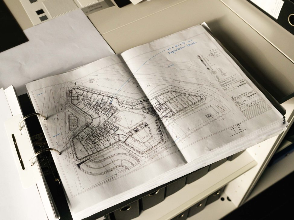 Architectural blueprints and plans in a ring binder on a desk.