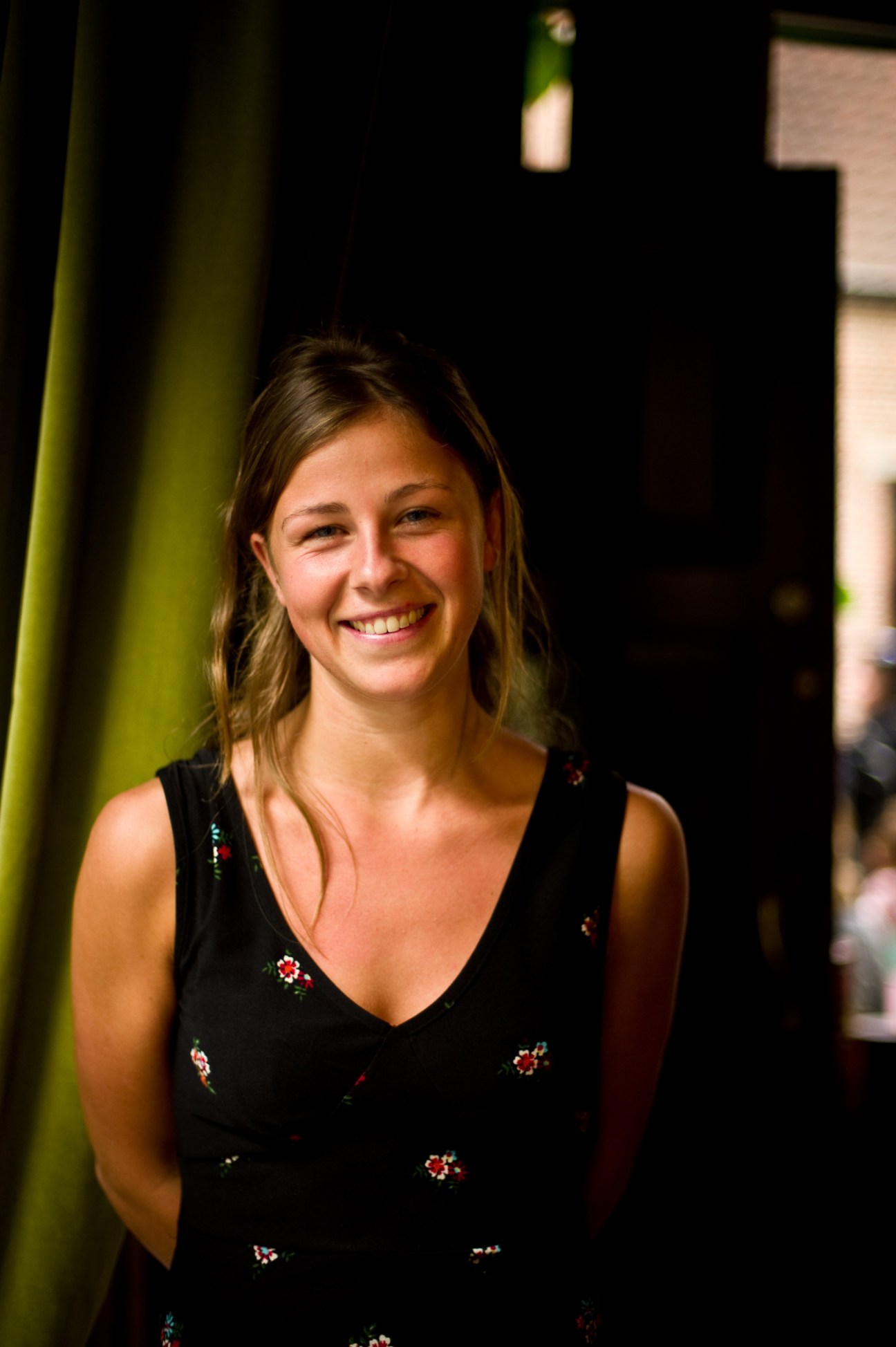 Caroline Van Ranst, waitress at Dansing Chocola, smiling against a dark background with green pillar.