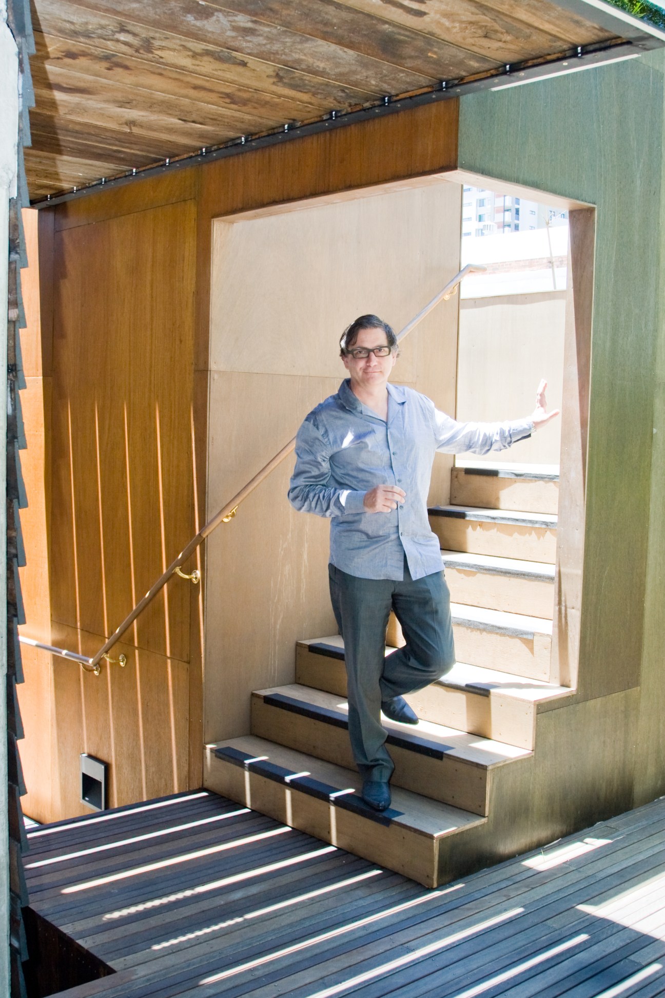 Timothy Hill, principal of Donovan Hill architects, standing on modern stairs with wooden and concrete materials in a contemporary architectural space.