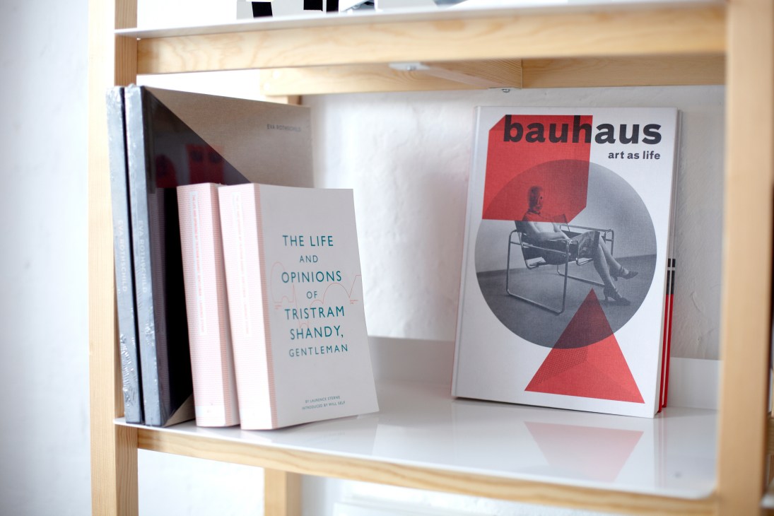 Books on a wooden shelf including Bauhaus art book and Tristram Shandy