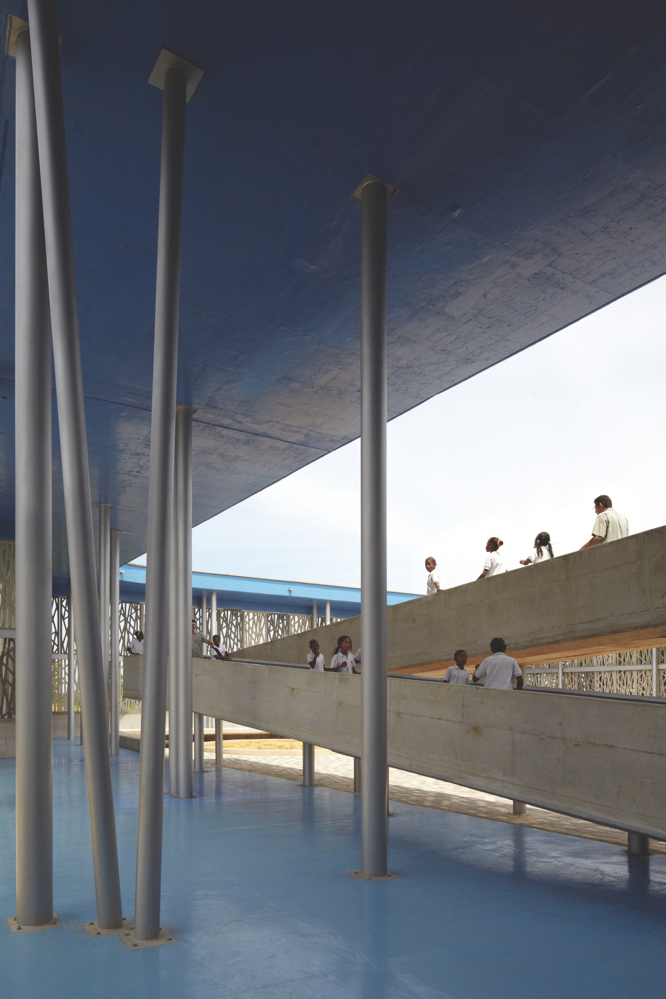 Children in a covered outdoor area of Wada kindergarten with concrete pillars and architectural elements inspired by traditional Japanese design.