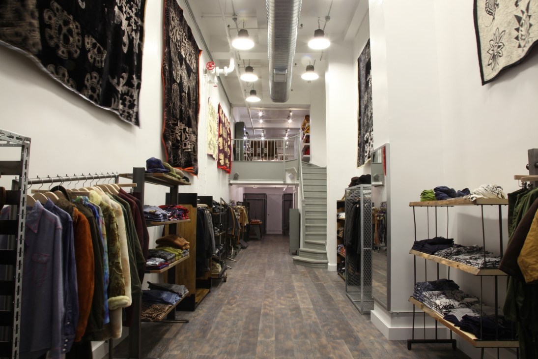Interior of Sketch boutique showing clothing displays on wooden shelves and racks with artistic prints on white walls.