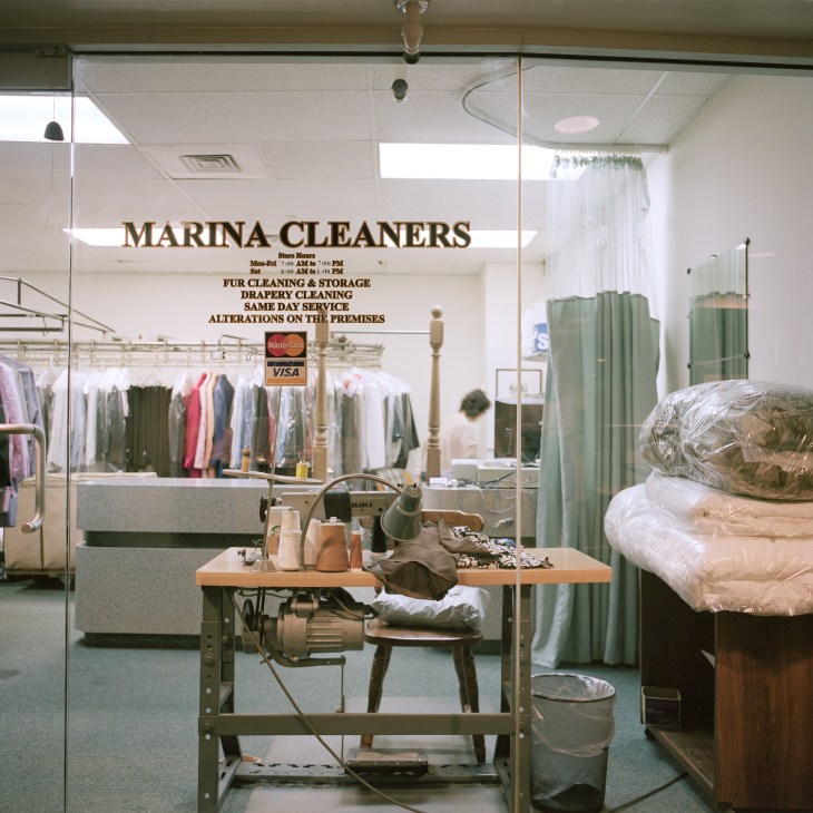 Interior of Marina City communal dry cleaning shop with counter, clothing racks, and pressed garments.