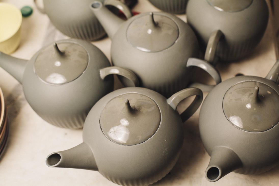 Minimalist porcelain teapots in soft grey with grooved handles and matching lids.