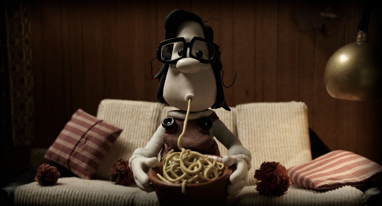 Animated character Max, a rotund figure with glasses, sitting on a couch eating noodles from a bowl.