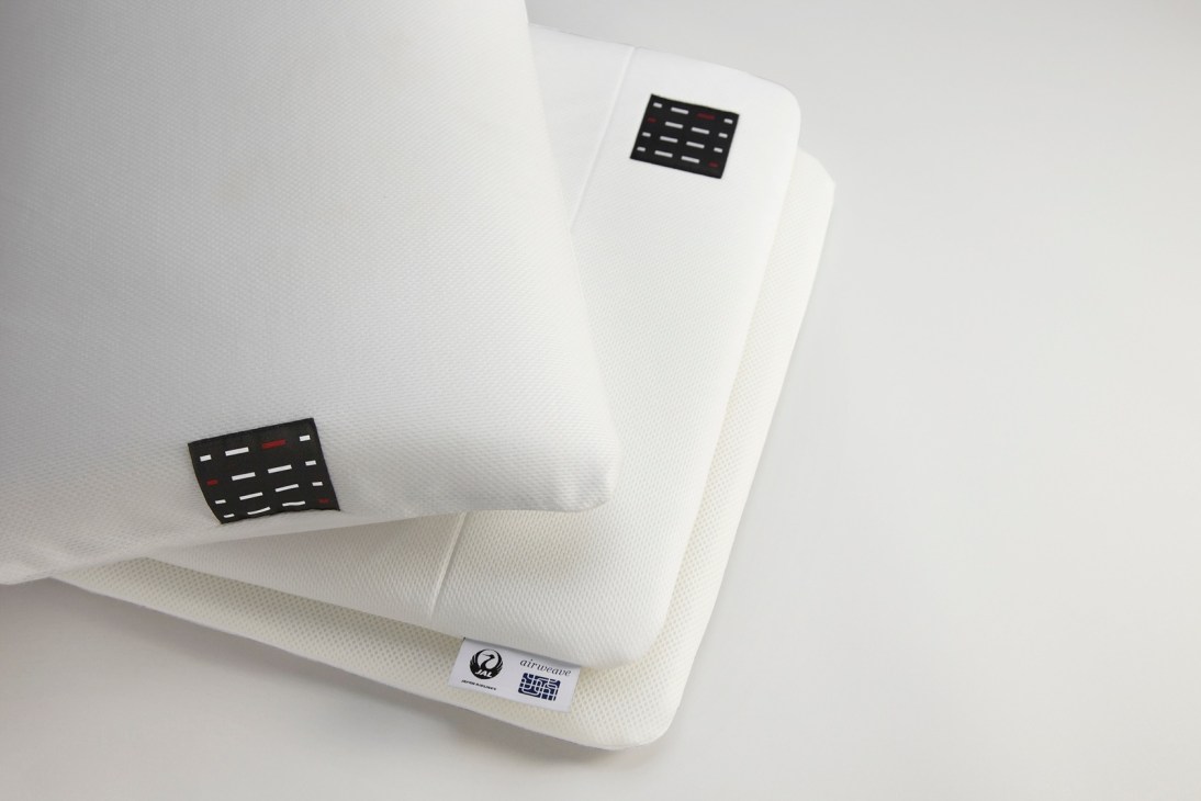 White airline pillow with black control panel details and branded labels.
