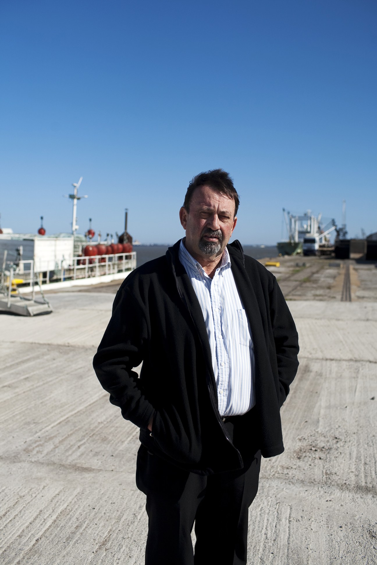 Captain Ken Shirley, port authority director, standing at Port Maputo with ships and cargo equipment visible behind him.