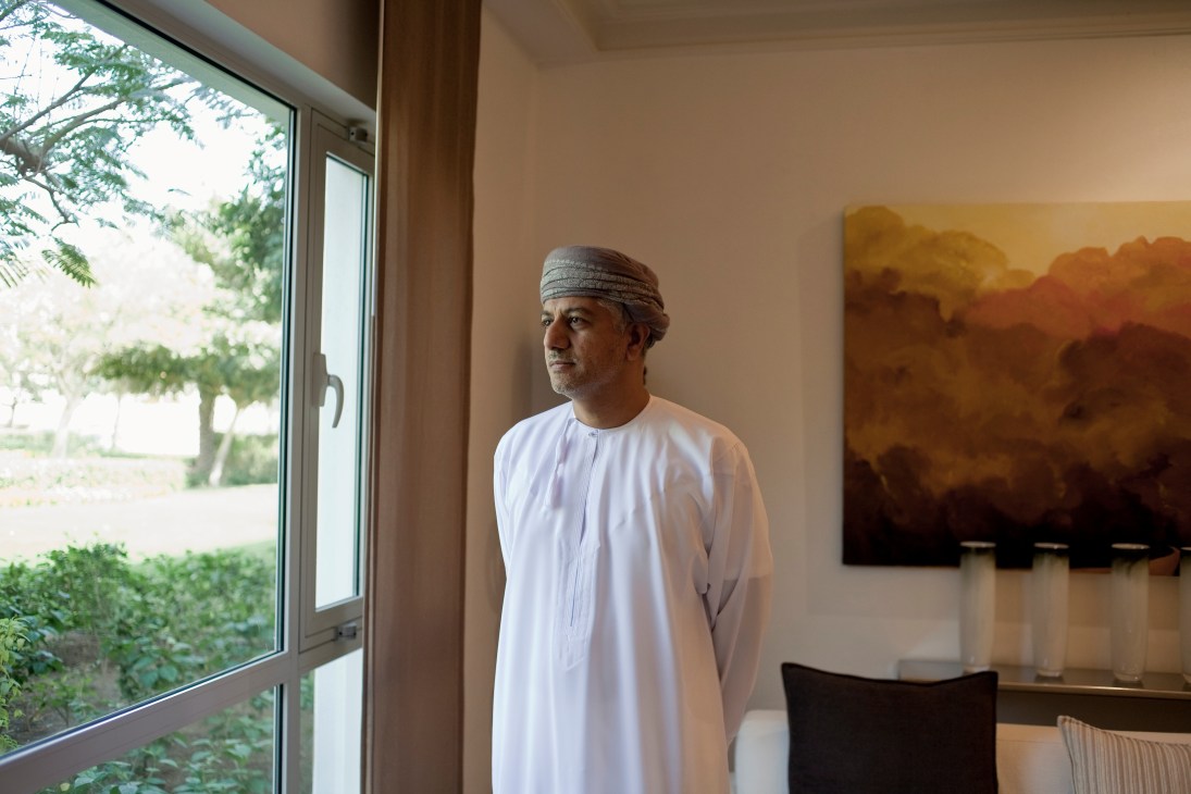 Khalid al Zubair, head of one of Oman's largest companies, stands in a modern office wearing traditional white dishdasha and grey cap.
