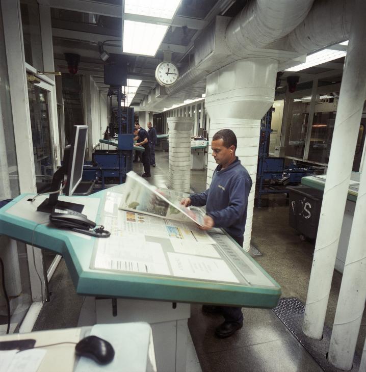A worker examines a freshly printed copy of Folha de S.Paulo newspaper at the printing plant.