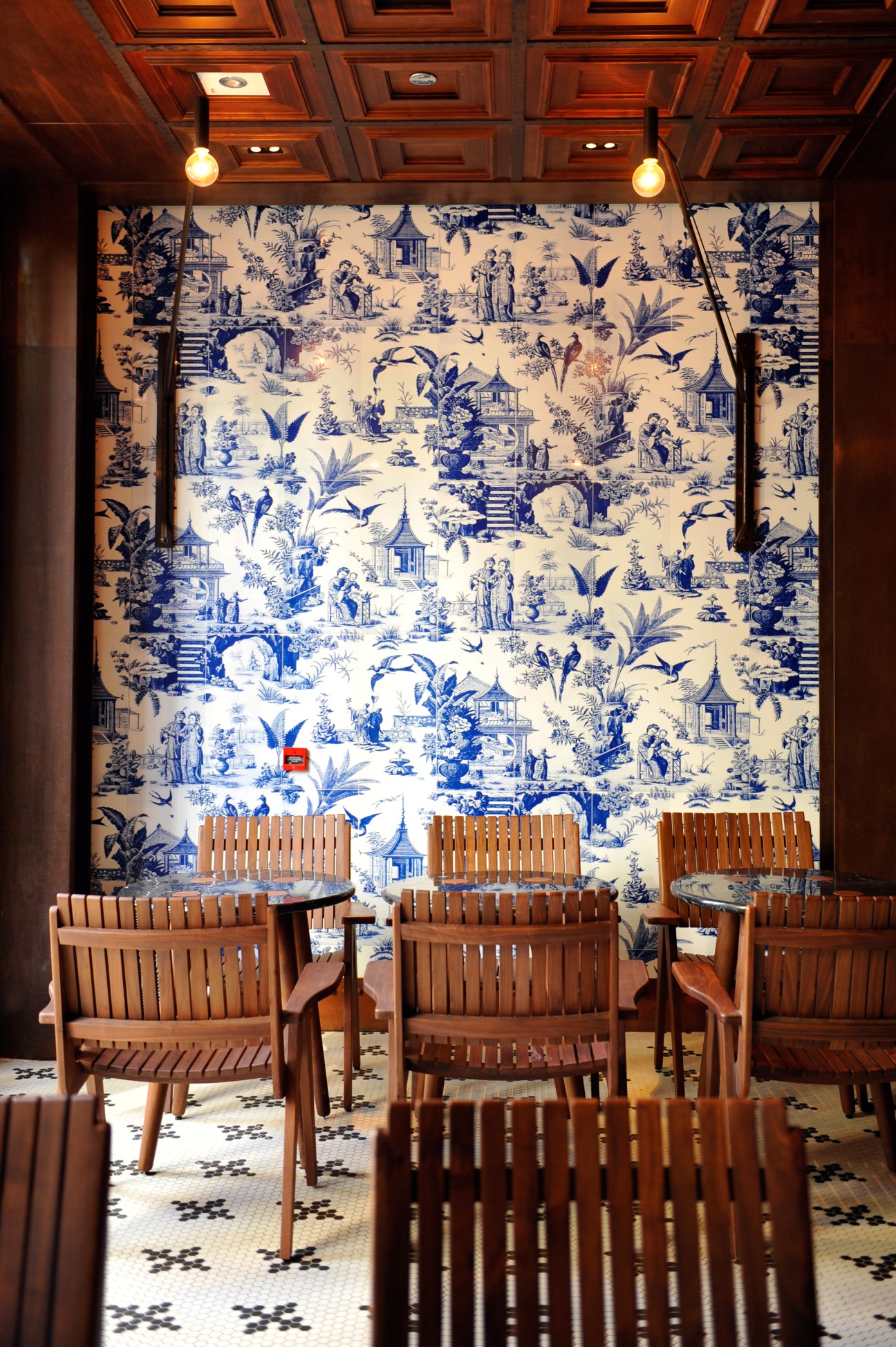 Interior of 208 Duecento Otto restaurant with wooden chairs and blue toile wallpaper.