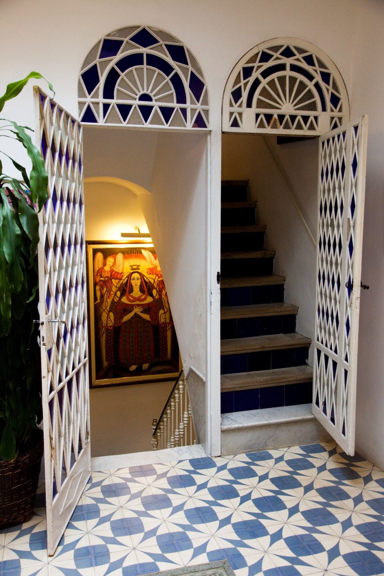 Ornate arched doorways with stained-glass panels and decorative tilework in a hallway.