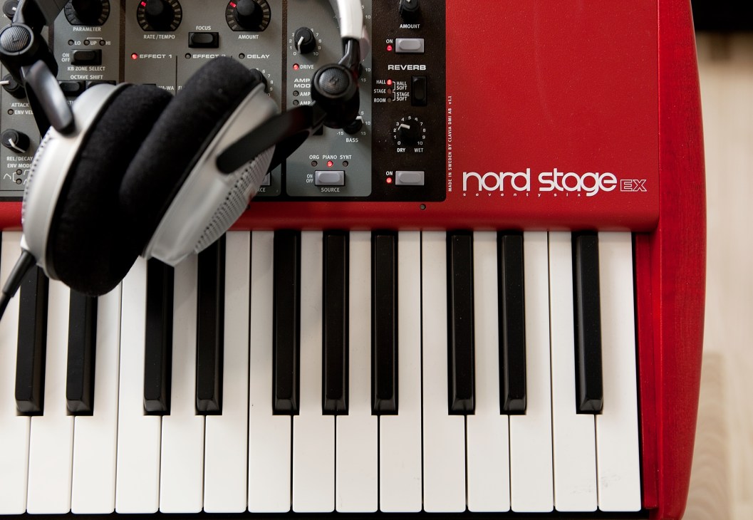 Nord Stage Ex keyboard in red with black and white keys, control panel and headphones.