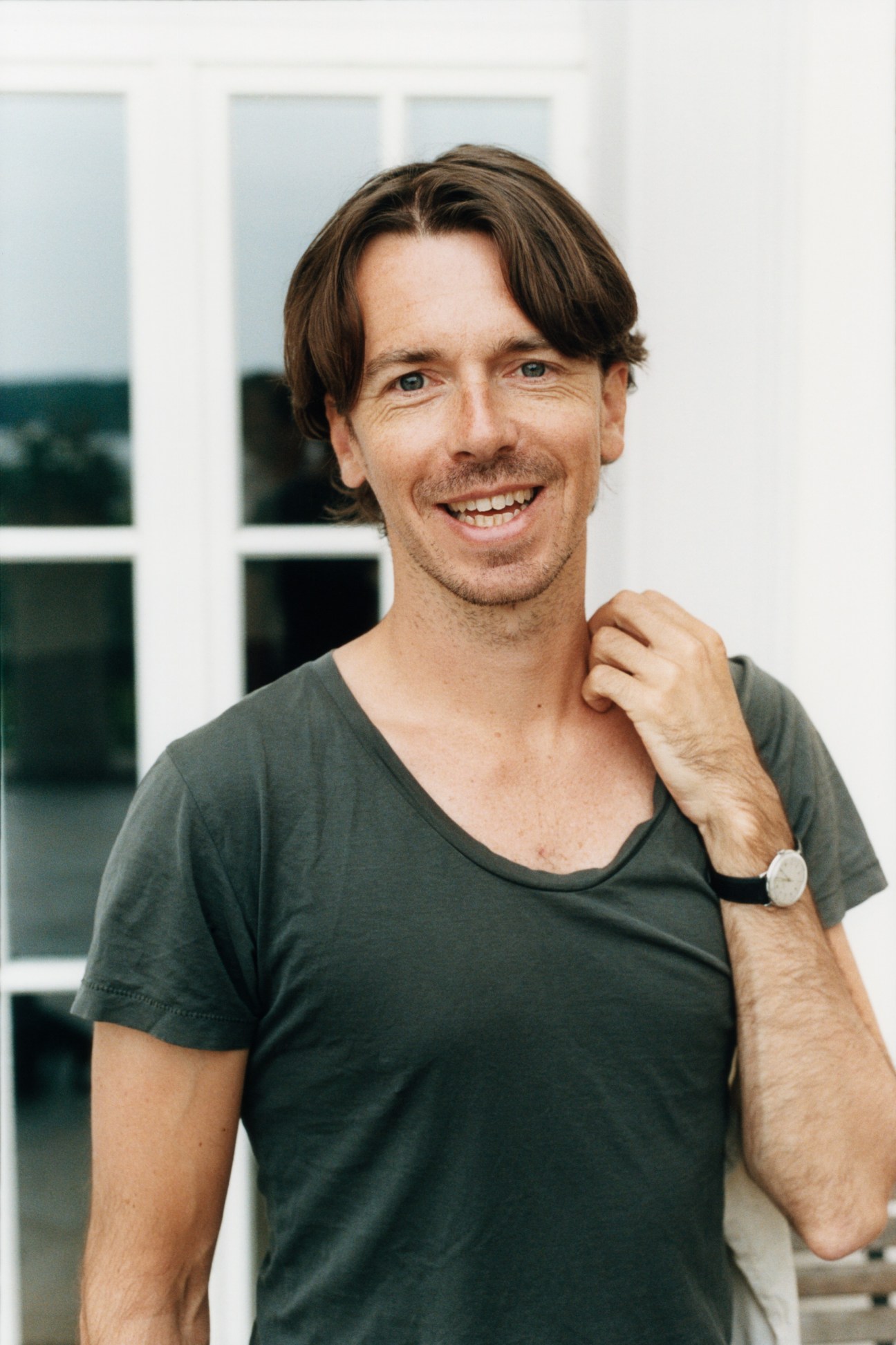 Portrait of American Academy fellow Leland de la Durantaye smiling at camera in front of windows.